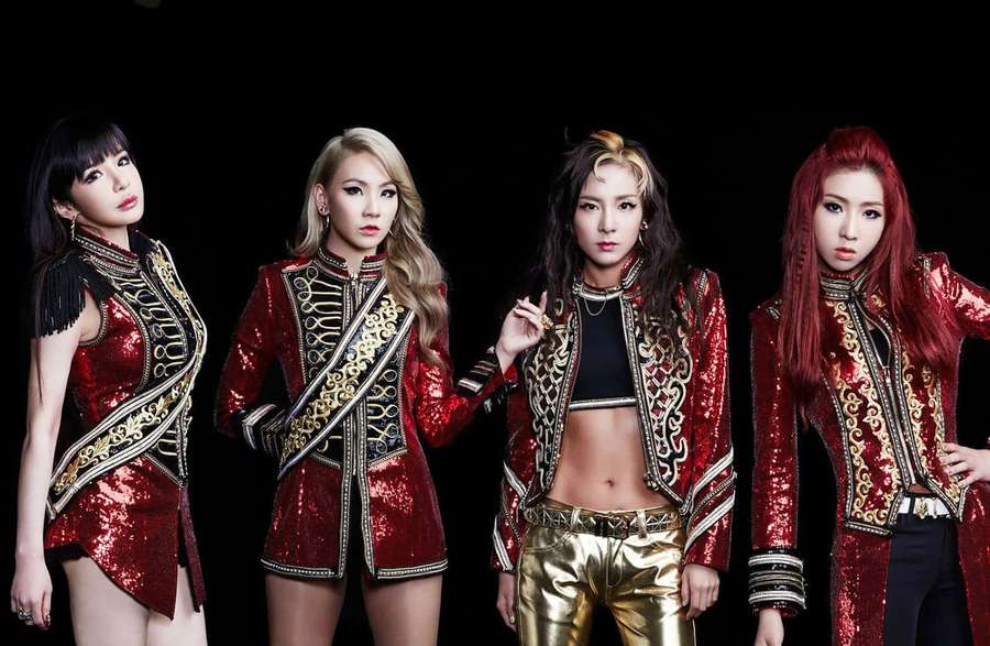 Vier Frauen in glänzenden rot-goldenen und schwarzen Bühnenoutfits posieren in einem Studio — 2ne1 Bilder