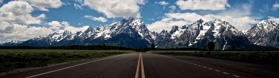 Long straight road leading to snow-capped mountains under a blue sky with clouds. — 3840X1080 Wallpaper