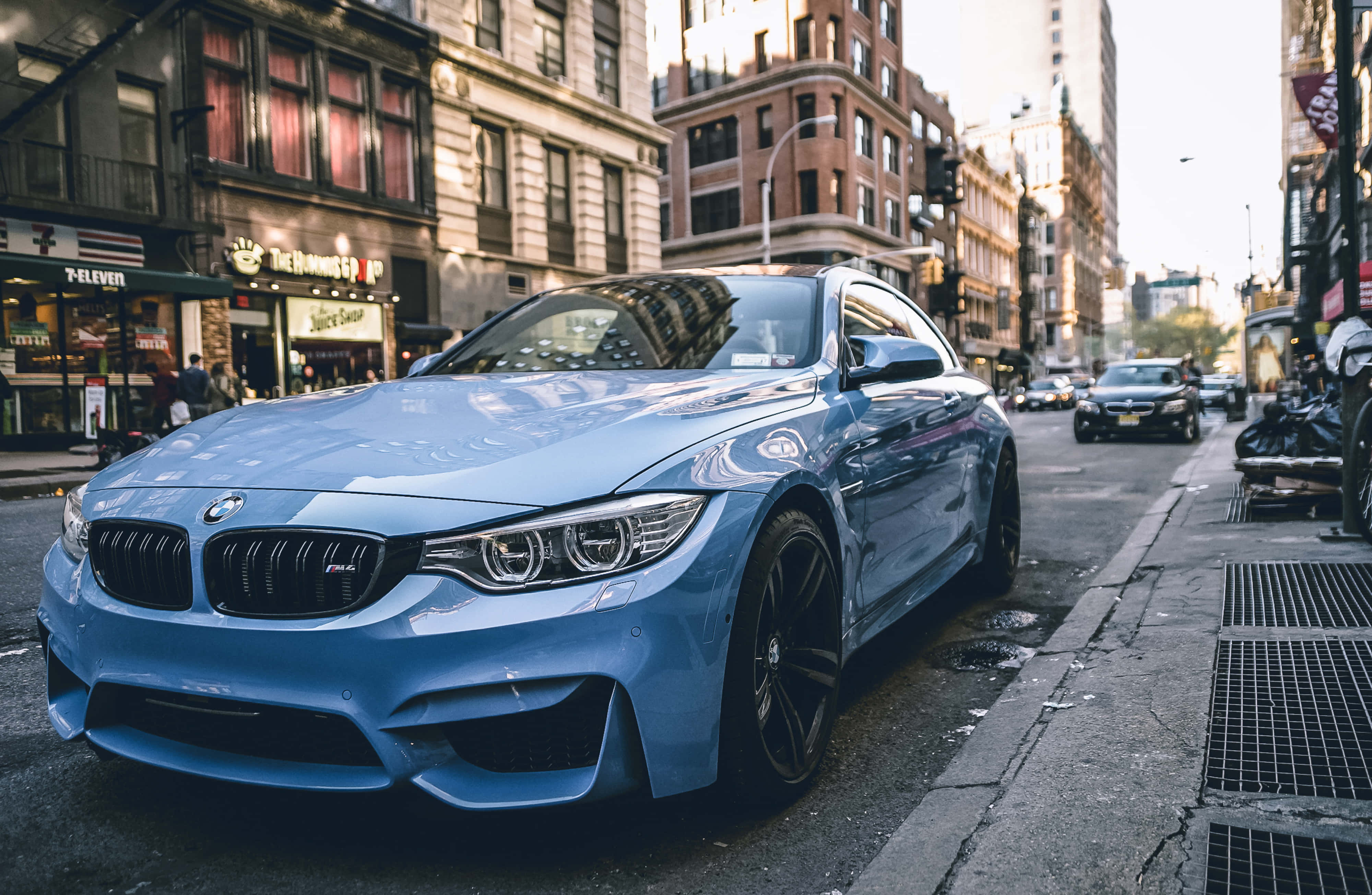 A blue BMW M4 parked on a city street at sunset. — 4K Bmw Wallpaper