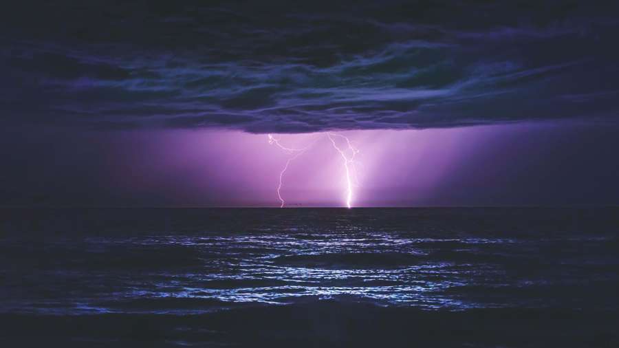 Purple lightning illuminates a dark ocean under a stormy night sky. — 4K Lightning Wallpaper