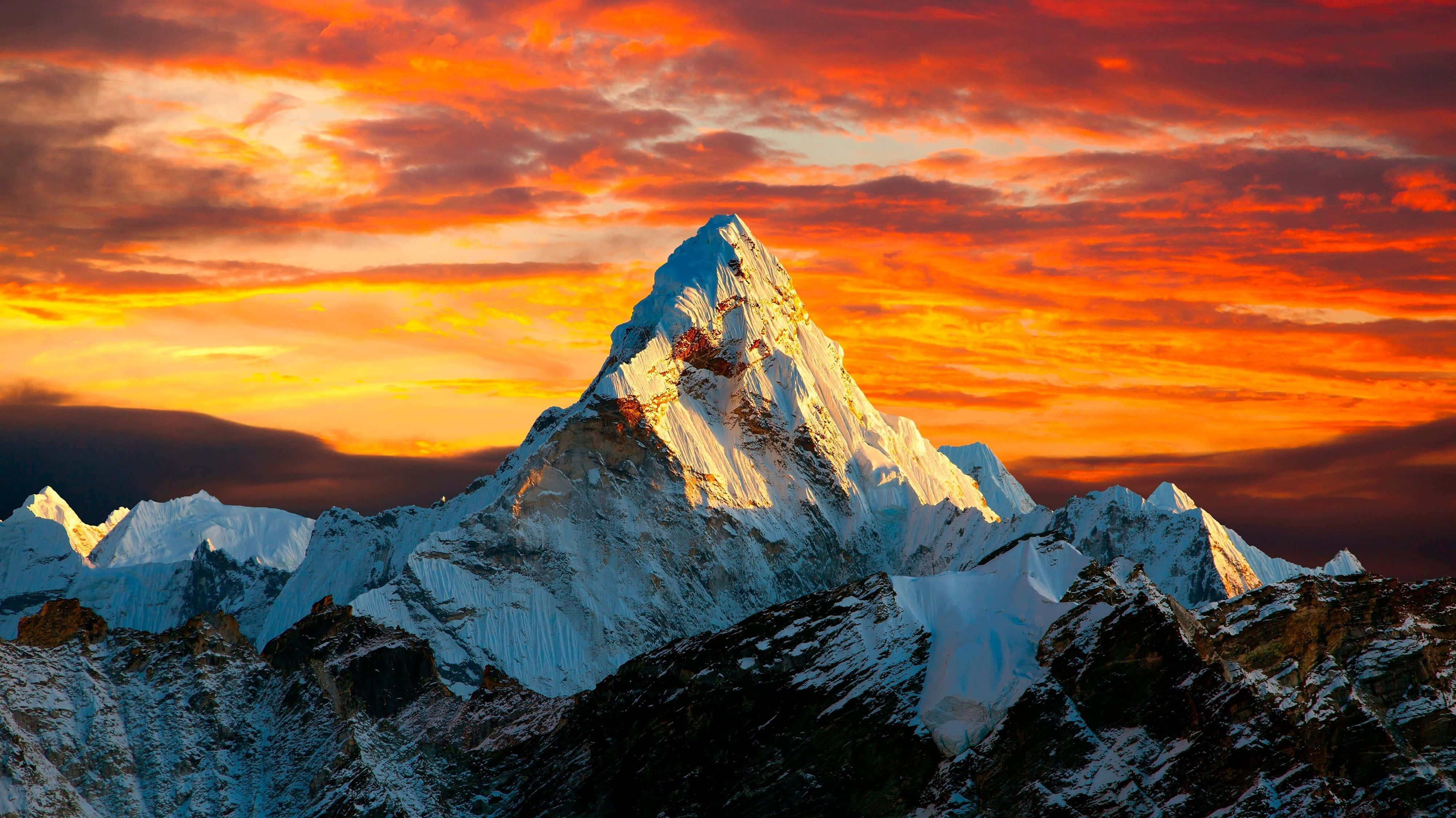 Snowy mountain peak at sunset with vibrant orange and red sky — 4K Mountain Wallpaper