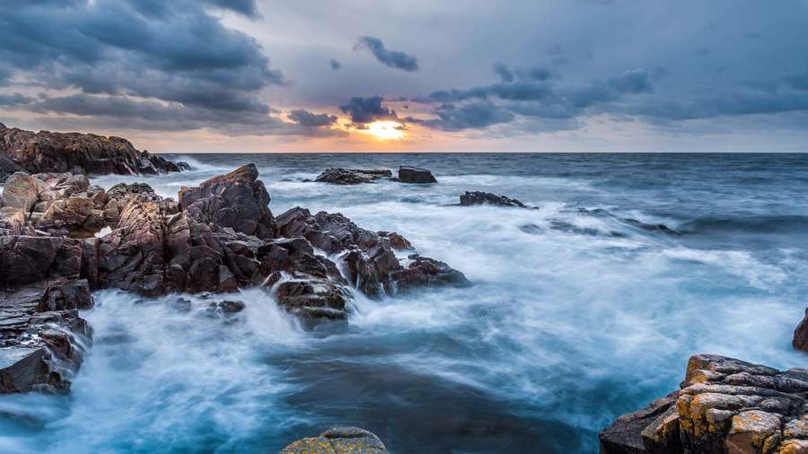 Sunset over rocky coastline with crashing waves and dramatic clouds. — 4K Ocean Wallpaper