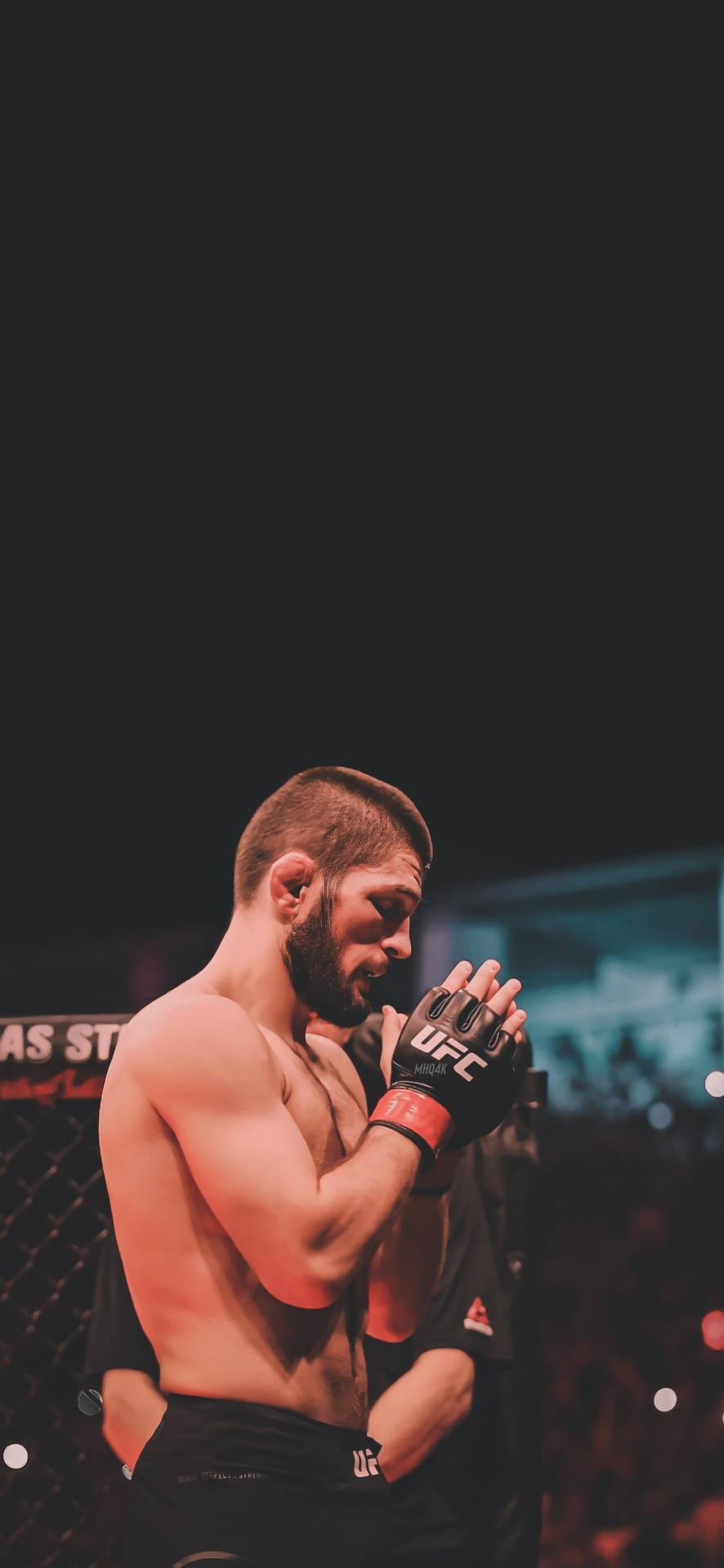 En fokuserad MMA-kämpe i UFC-utrustning står inne i en oktagon med händerna knäppta nära ansiktet. — 4K Upplösning Bakgrundsbilder
