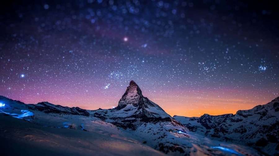 Verschneiter Berggipfel unter einem sternenklaren Dämmerungshimmel mit lila und orangen Farbtönen. — 720p Bilder