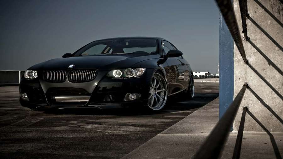 Black BMW coupe parked on rooftop near concrete wall with strong shadows. — 720p Bmw Background