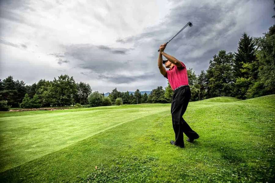Golfer swinging club on green golf course with trees and cloudy sky. — 720p Golf Background