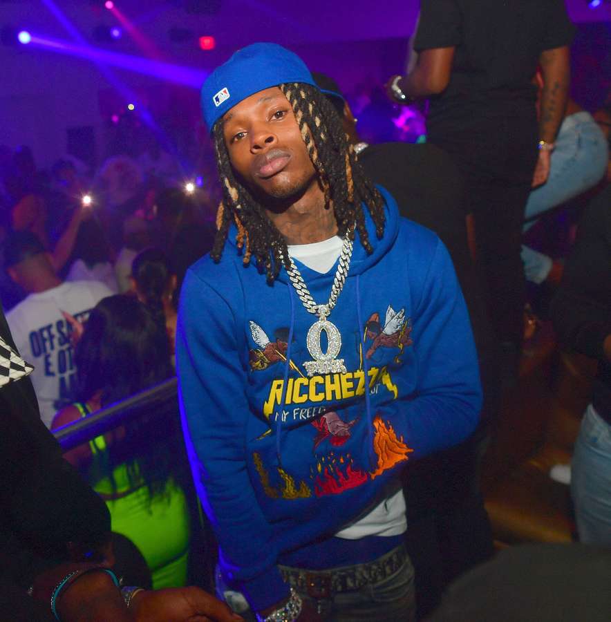 Young man in blue hoodie and cap at a lively nightclub party. — 90s Rapper Background
