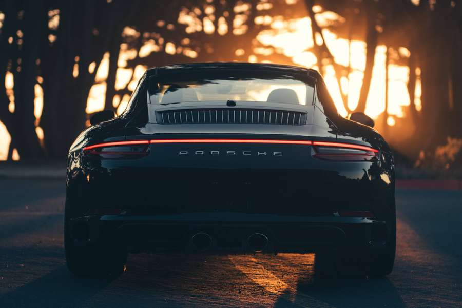 Black Porsche sports car parked on road at golden sunset in forest. — 911 Wallpaper