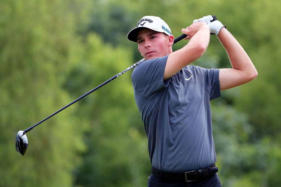 Golfer swinging club on green course with trees behind — Aaron Wise Wallpaper
