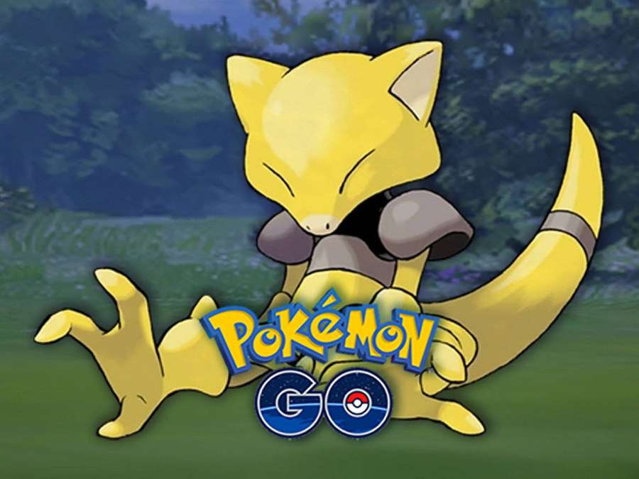 Yellow cat Pokémon sitting in grass with forest background and Pokémon GO logo. — Abra Background