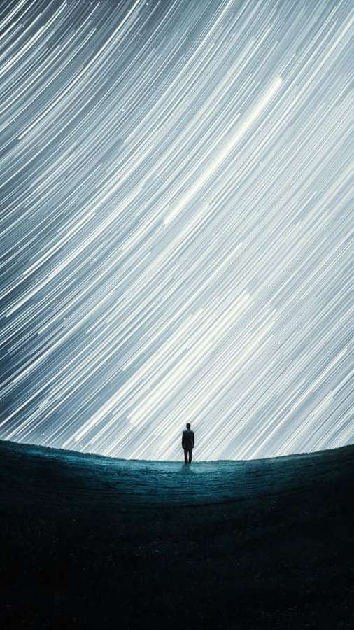 Silhouette of a person standing alone under a sky of streaking stars. — Abstract Portrait Wallpaper