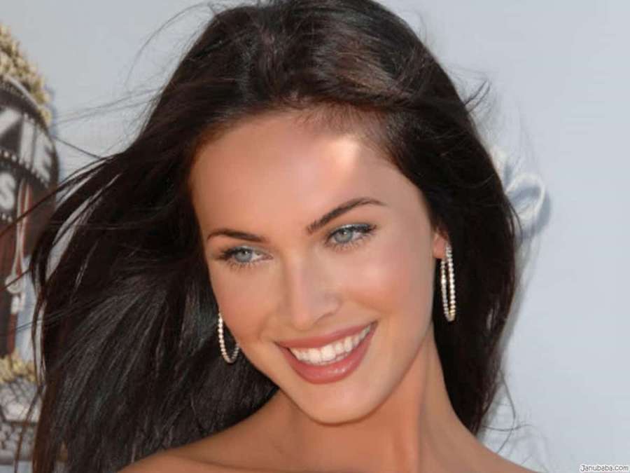 A smiling woman with dark hair and blue eyes wearing dangling earrings at an event. — Actress Picture