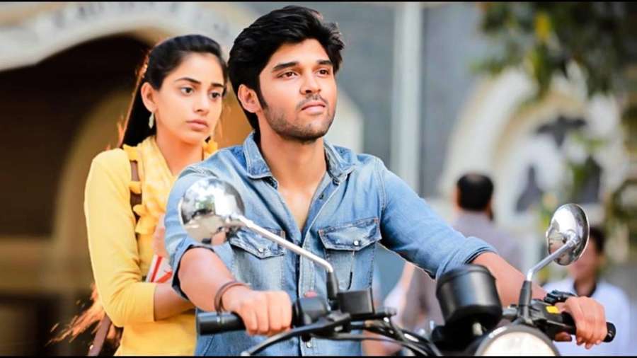 Man riding motorcycle with woman behind him on city street — Adithya Varma Wallpaper
