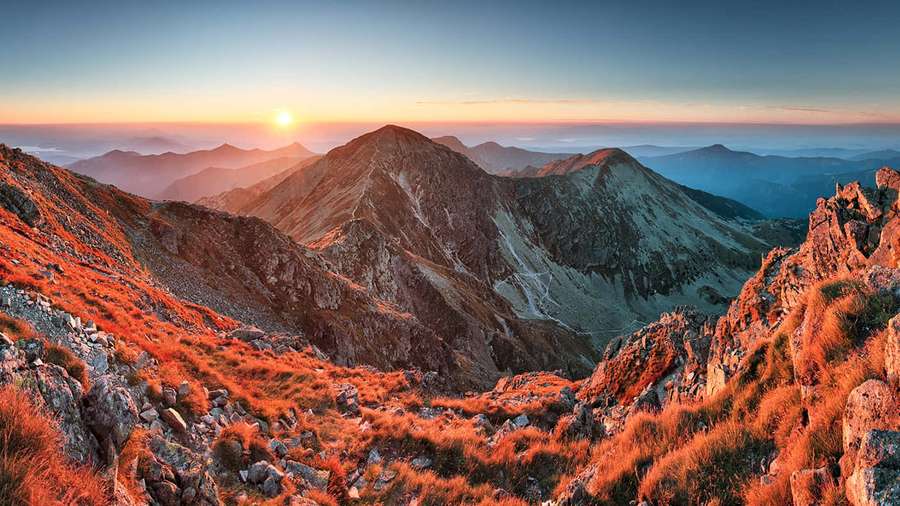 Sunrise over rugged mountains with golden grasses and layered peaks. — Adobe Picture