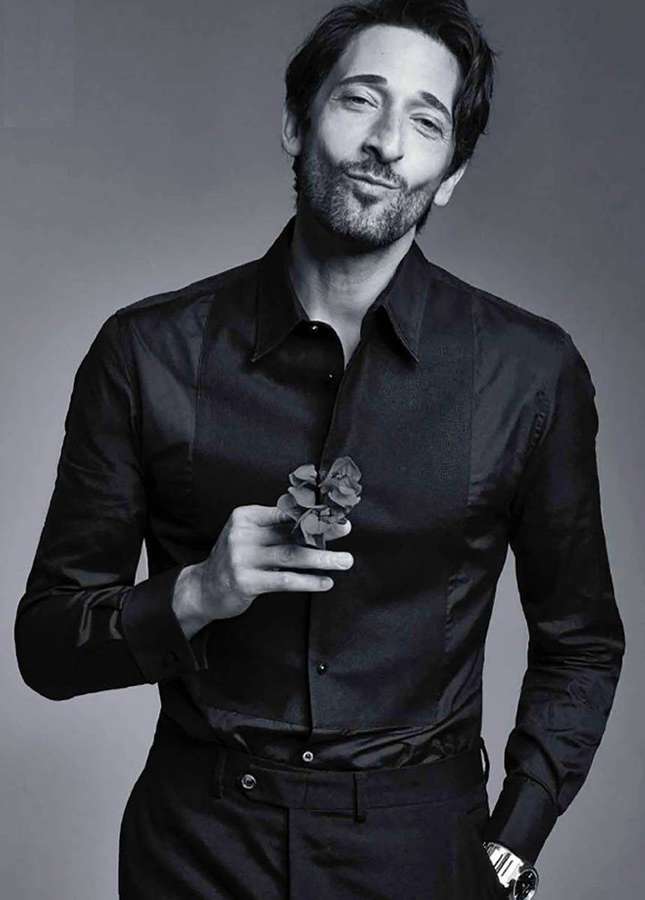 A man in a black shirt holding a flower and smiling at the camera. — Adrien Wallpaper