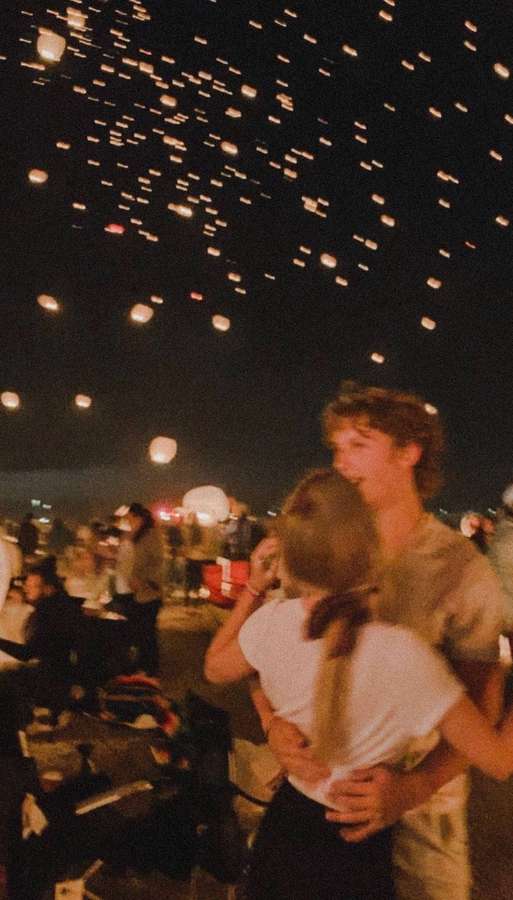 A couple embraces as glowing lanterns float above them at night. — Aesthetic Couple Wallpaper