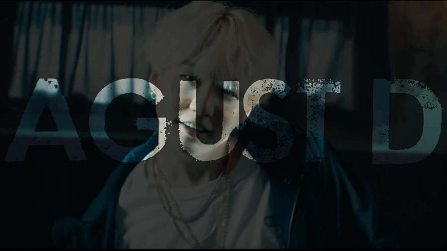 Person with platinum blonde hair in a dark room with large text overlay. — Agust D Wallpaper