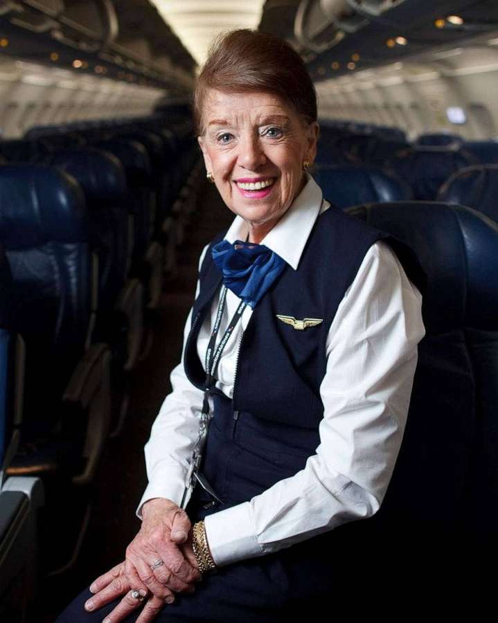 Elderly flight attendant smiling in airplane cabin — Airlines Background