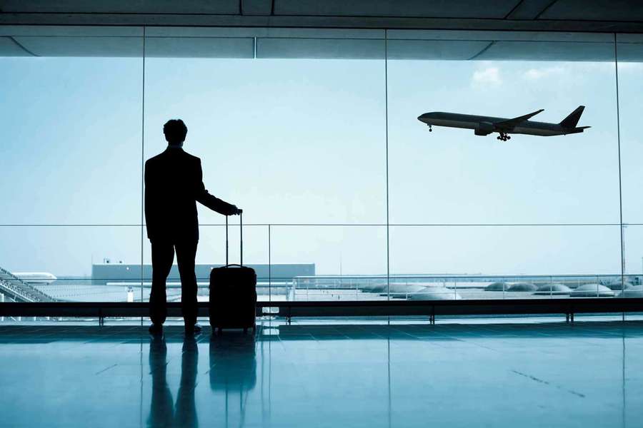Man with suitcase watching plane land at airport terminal. — Airport Background