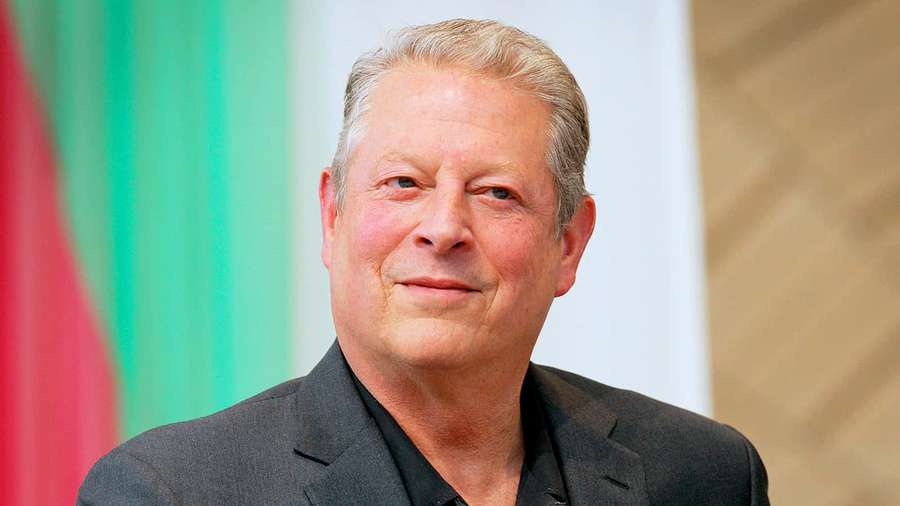 A smiling older man in a dark suit posing indoors with colorful background. — Al Gore Wallpaper