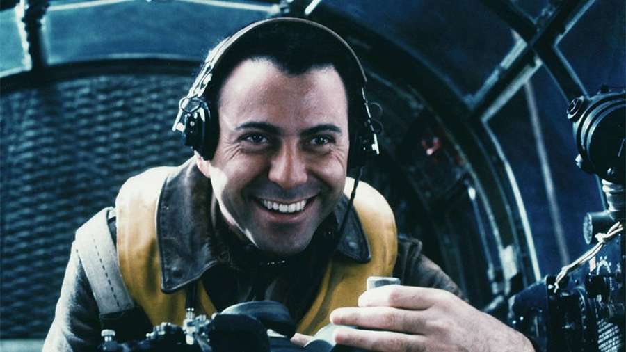 Pilot im Cockpit lächelt, während er eine Tasse hält und Kopfhörer trägt. — Alan Arkin Bilder