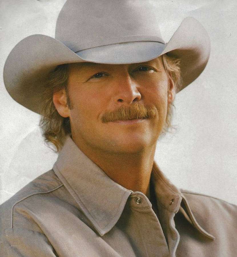 A smiling man wearing a cowboy hat and shirt. — Alan Jackson Background