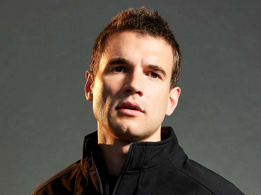 Close-up portrait of a man in a black jacket looking directly at camera. — Alex Russell Wallpaper