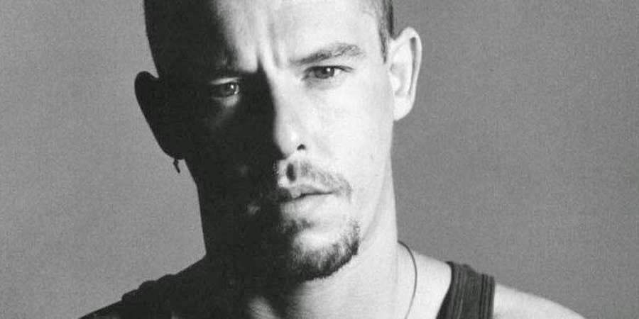 Close-up black and white portrait of a serious man with shaved head and stubble. — Alexander Mcqueen Background