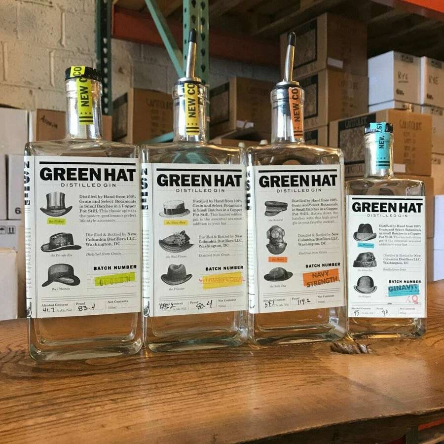 Vier Flaschen Green Hat Distilled Gin mit Hut-etikettierten Etiketten auf einem Holzregal in einem Lager. — Alkohol Wallpaper