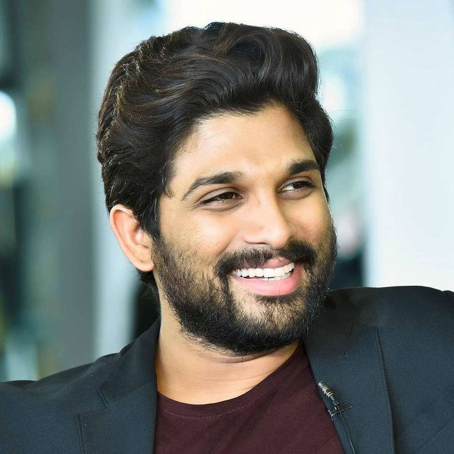 Ein Mann mit Bart lächelt, während er einen Blazer und ein weinrotes Hemd trägt. — Allu Arjun Bilder
