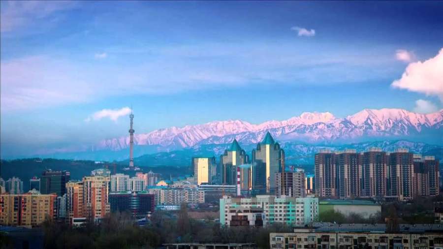 Stadtsilhouette mit schneebedeckten Bergen im Hintergrund in der Dämmerung. — Almaty Bilder