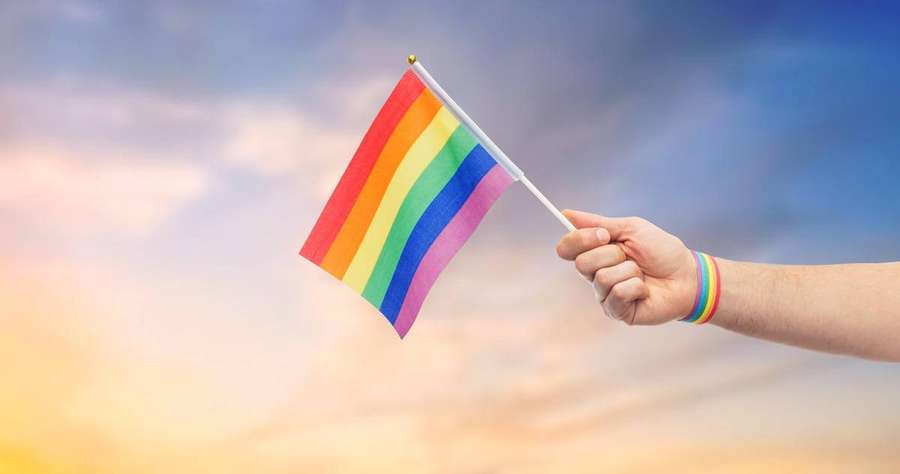 Mão segurando bandeira arco-íris ao pôr do sol — Amor é amor Papéis de Parede
