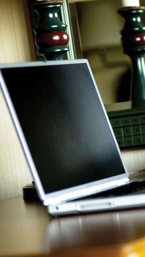 Silver laptop on wooden desk with green candlesticks in background — Android Computer Picture