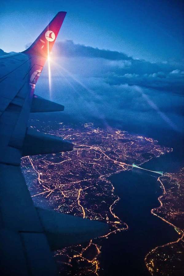 Aircraft wing silhouetted against glowing city lights at dusk. — Android Plane Background