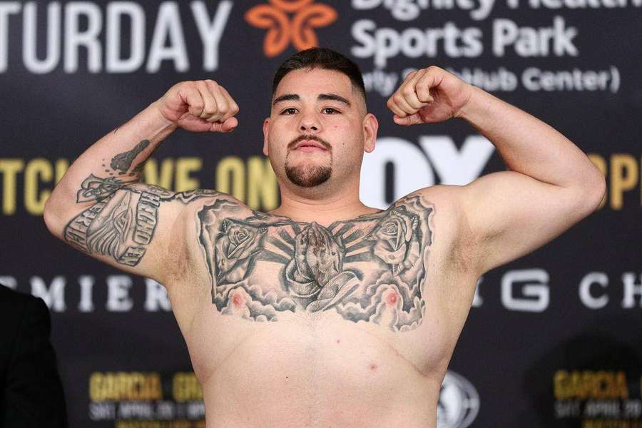 Tatuoitu nyrkkeilijä jännittää lihaksia punnitustapahtumassa — Andy Ruiz Taustakuvat
