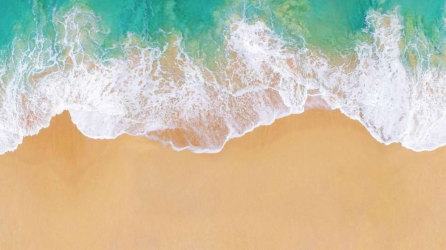 Türkisfarbene Wellen rollen sanft auf goldenen Sand von oben. — Apple Beach Wallpaper