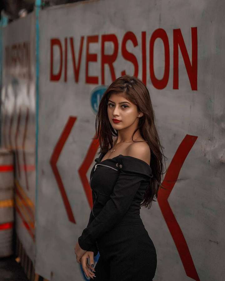 Woman in black dress posing near diversion sign on concrete wall. — Arishfa Khan Background