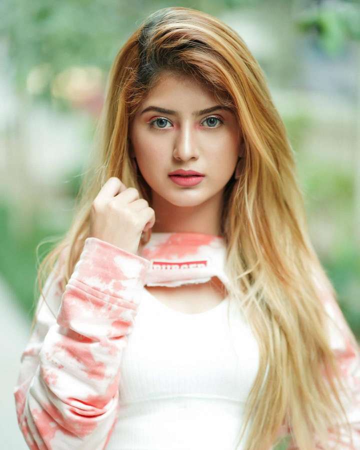 Junge Frau mit blonden Haaren und blauen Augen, die einen pinkfarbenen Tie-Dye-Hoodie trägt. — Arishfa Khan Bilder