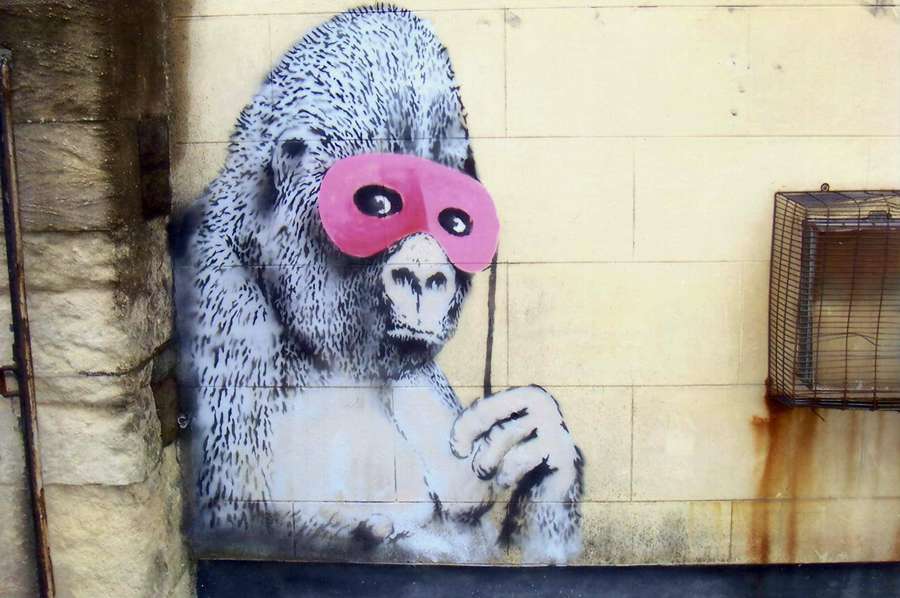 Mural de gorila con máscara rosa sosteniendo bastón en pared urbana con jaula oxidada. — Arte de Gorila Fondos de pantalla