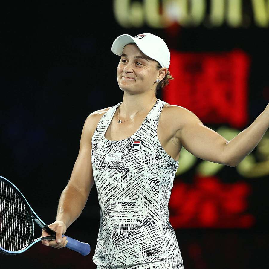 Tennisspielerin feiert Sieg mit erhobenem Arm und Schläger unter Stadionlichtern. — Ashley Barty Wallpaper