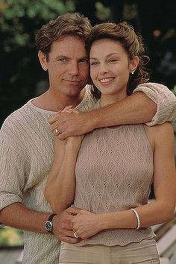 A happy couple embracing in a sunny outdoor setting with greenery. — Ashley Judd Background