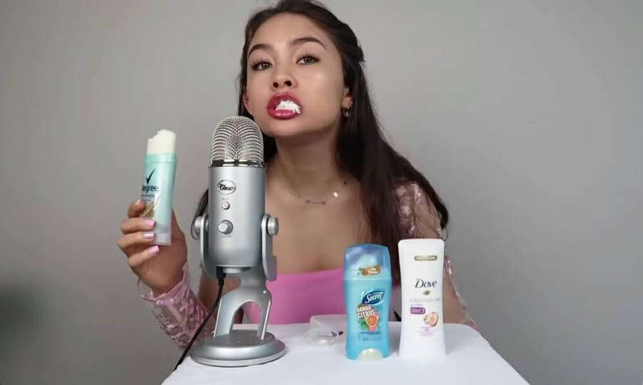 Frau hält Deodorant vor einem Mikrofon mit anderen Produkten auf dem Tisch. — Asmr Hintergrundbild