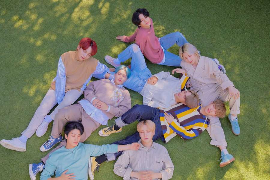 Seven young men in casual clothes lounging in a circle on green grass. — Ateez Wallpaper