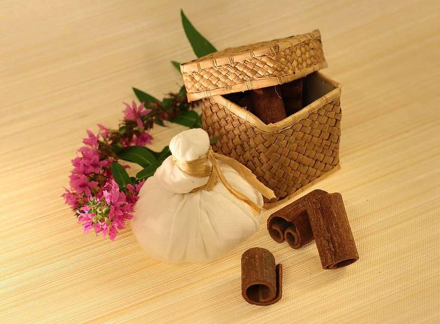 Palitos de canela, flores y un envoltorio de tela sobre una esterilla de bambú. — Ayurveda HD Fondos de pantalla