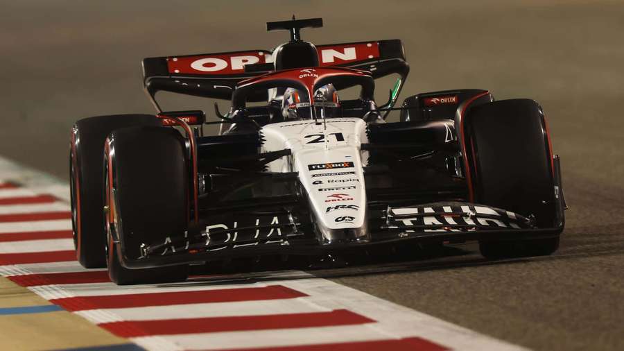 Formula 1 race car number 21 speeding on a night track with red and white curbing. — Bahrain Gp Wallpaper