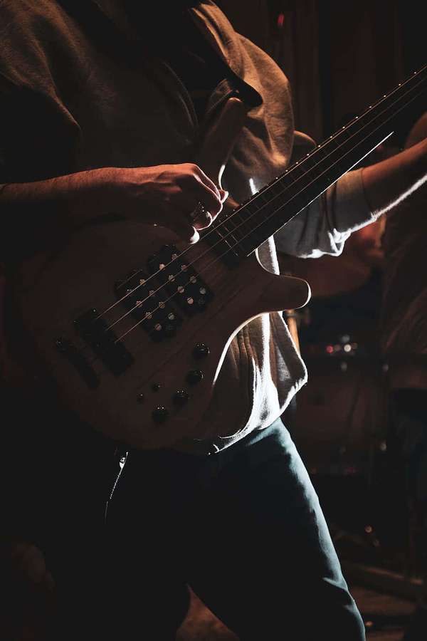Un músico tocando el bajo en el escenario bajo luces cálidas — Bajo eléctrico Fondos de pantalla