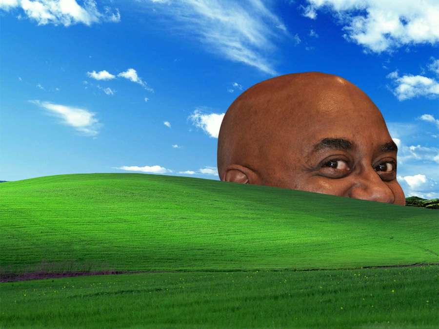 Giant bald man peeking over a green hill under a blue sky. — Bald Man Background