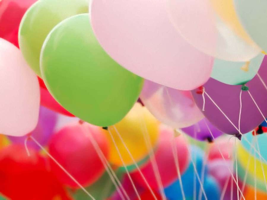 A cluster of colorful balloons floating with strings trailing down. — Balloons Background