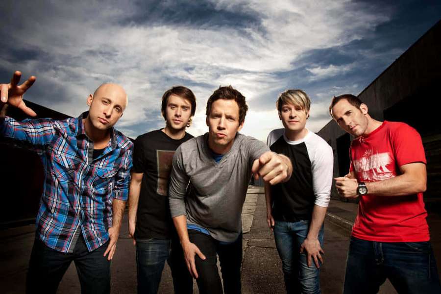 Five men posing in an urban alley with dramatic sky behind them. — Band Picture