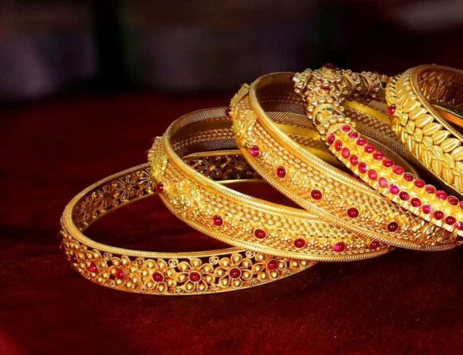 Stack of intricate gold bangles with red stones on red velvet background. — Bangles Picture